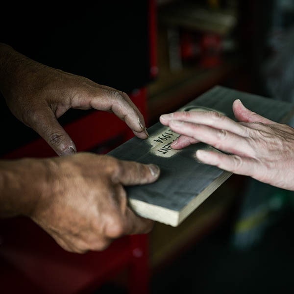 製作中の看板に触れる職人の画像