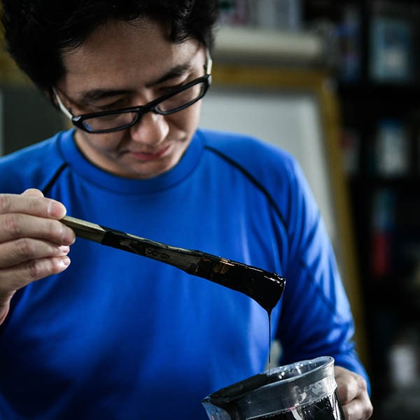 塗料を見つめる看板職人の画像