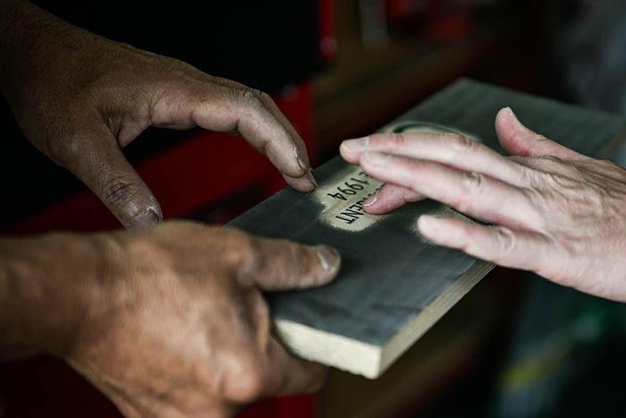 製作中の看板に触れる職人の画像